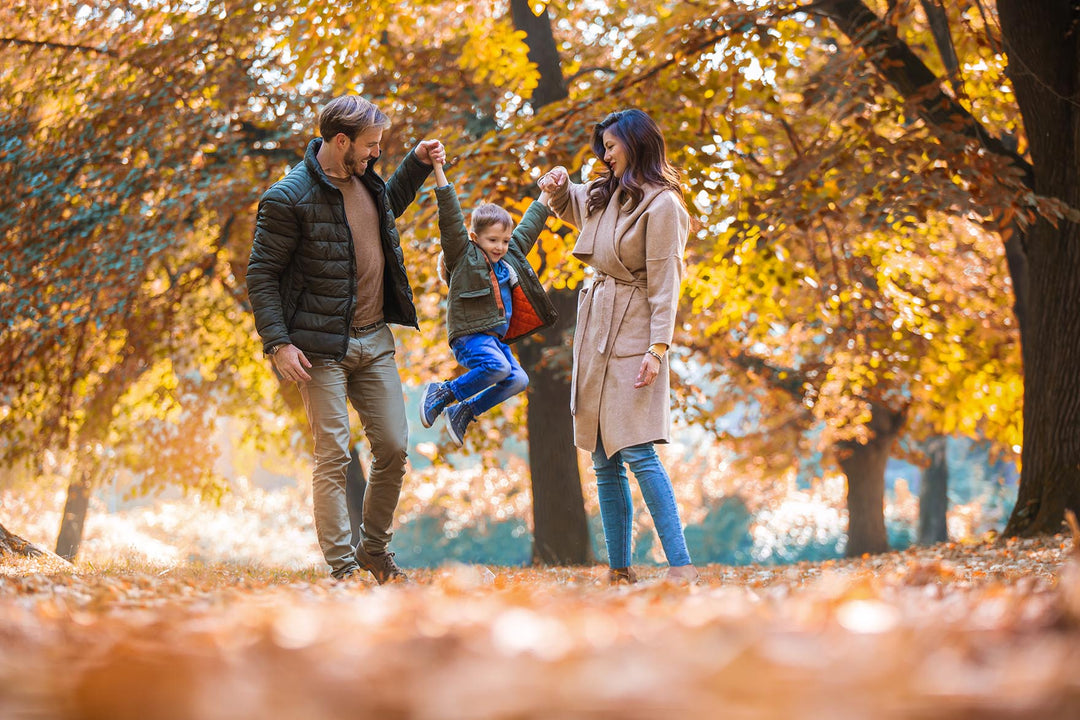 Family holding hands and playing in the leaves, Fall