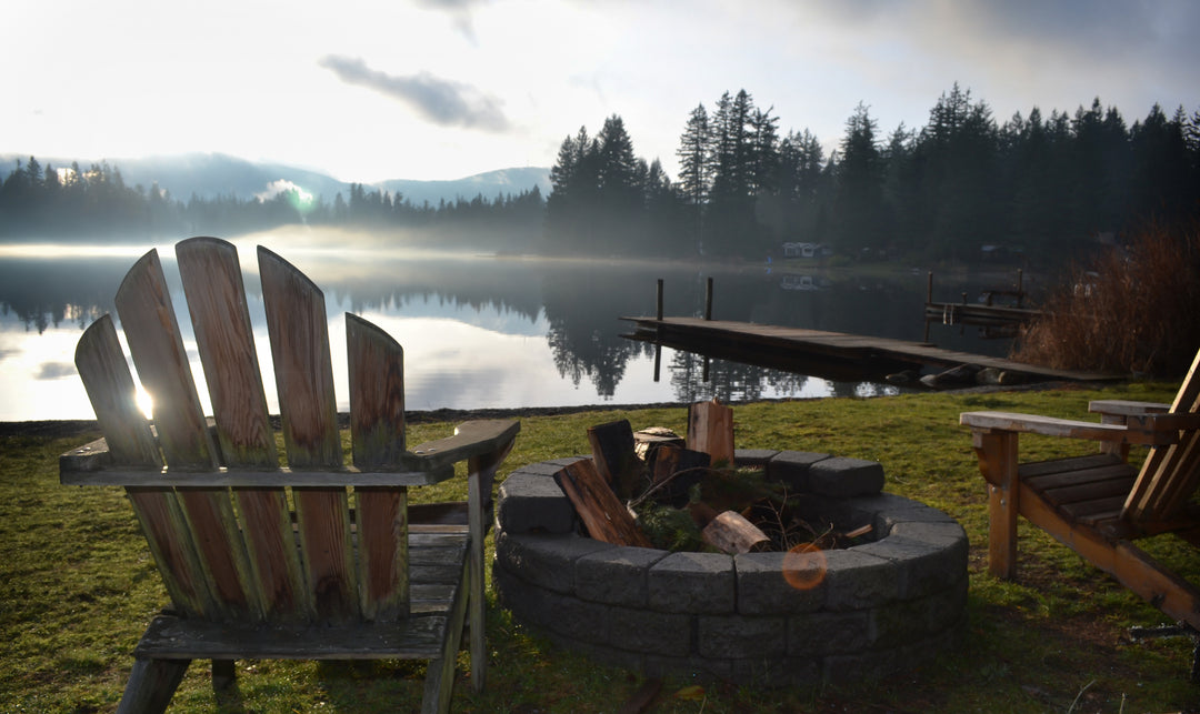Two Adirondack Chairs around a fire pit with a view of the lake in the background