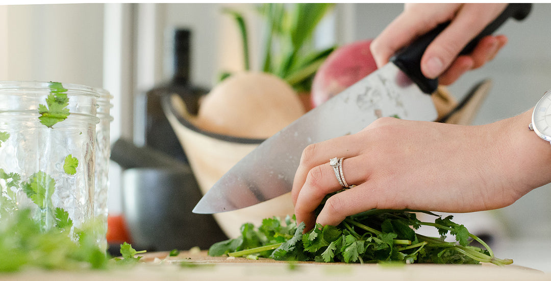 Woman cutting vegetables on wooden cutting board. 