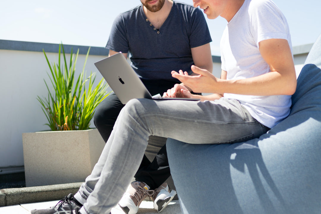 two co-workers sitting outside next to planters.